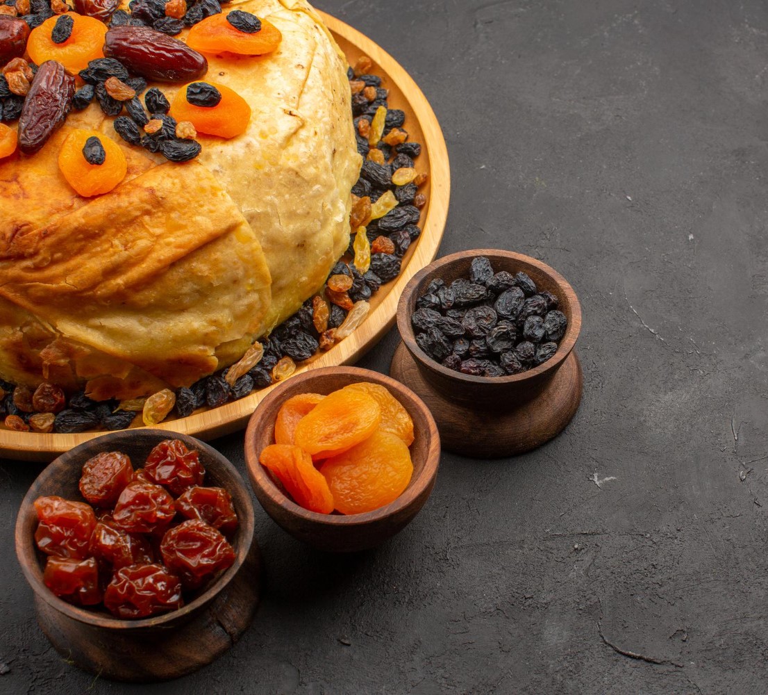 Platter of pilaf topped with dried apricots, dates and raisins beside bowls of dried fruit