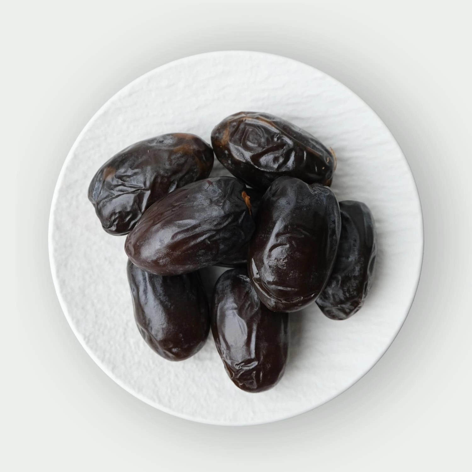 Large dark Medjool dates on a plate